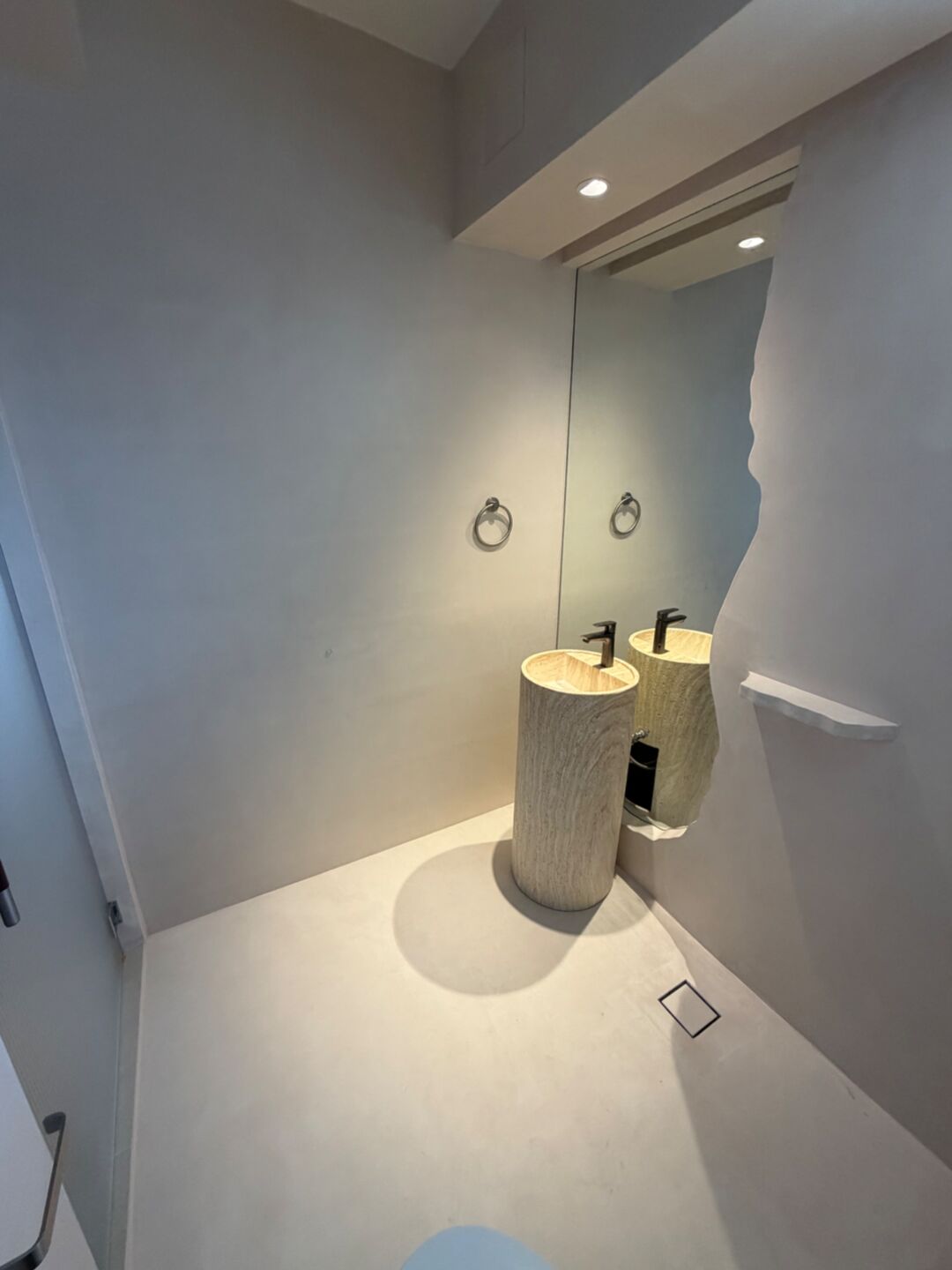 Microcement bathroom walls and floor around a timber pedestal basin
