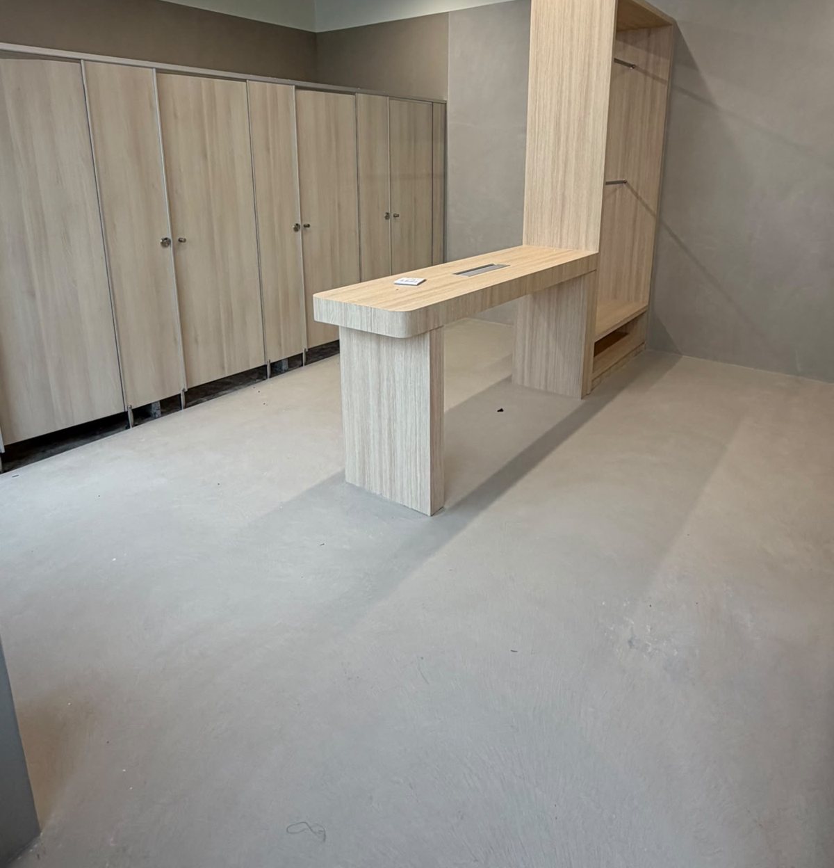 Seamless microcement floor in front of timber changing cubicles and a counter