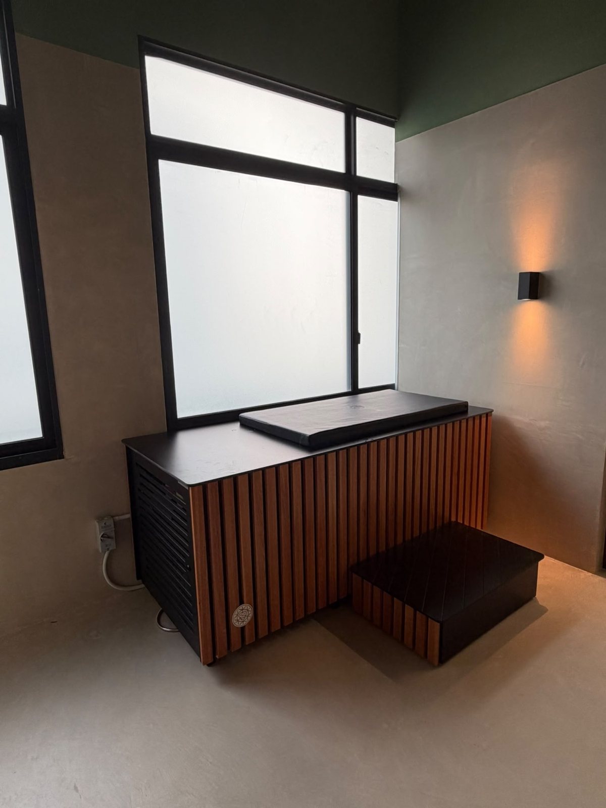 Microcement walls and floor beside a slatted timber bench under a window