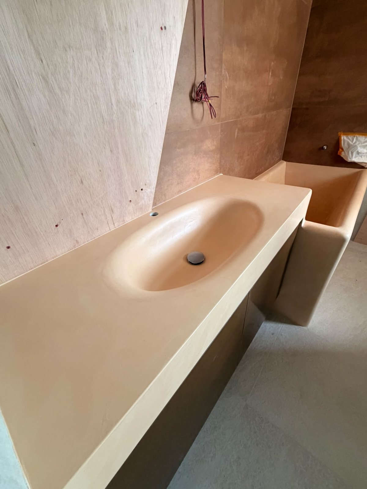 Microcement basin and vanity in one continuous warm finish