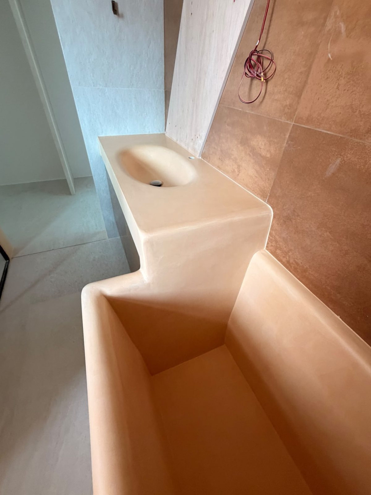 Microcement basin counter stepping down into a built-in tub, moulded in one piece