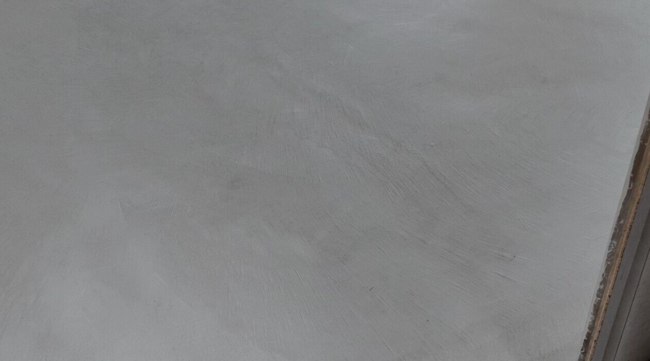 Raw and cloudy microcement wall in raking light